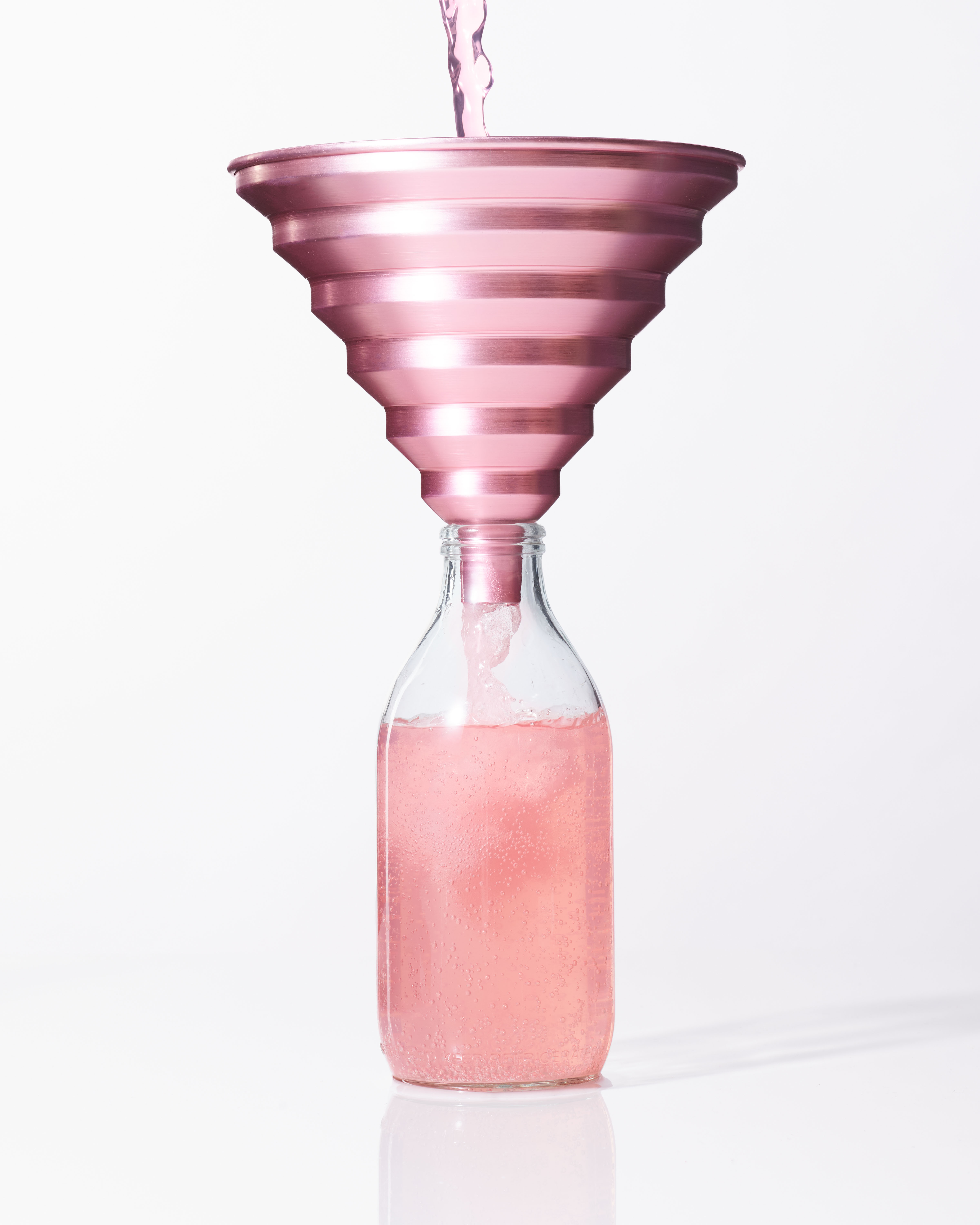 Image of a pink anodised stepped edge aluminium kitchen funnel with pink lemonade being poured through it into a bottle