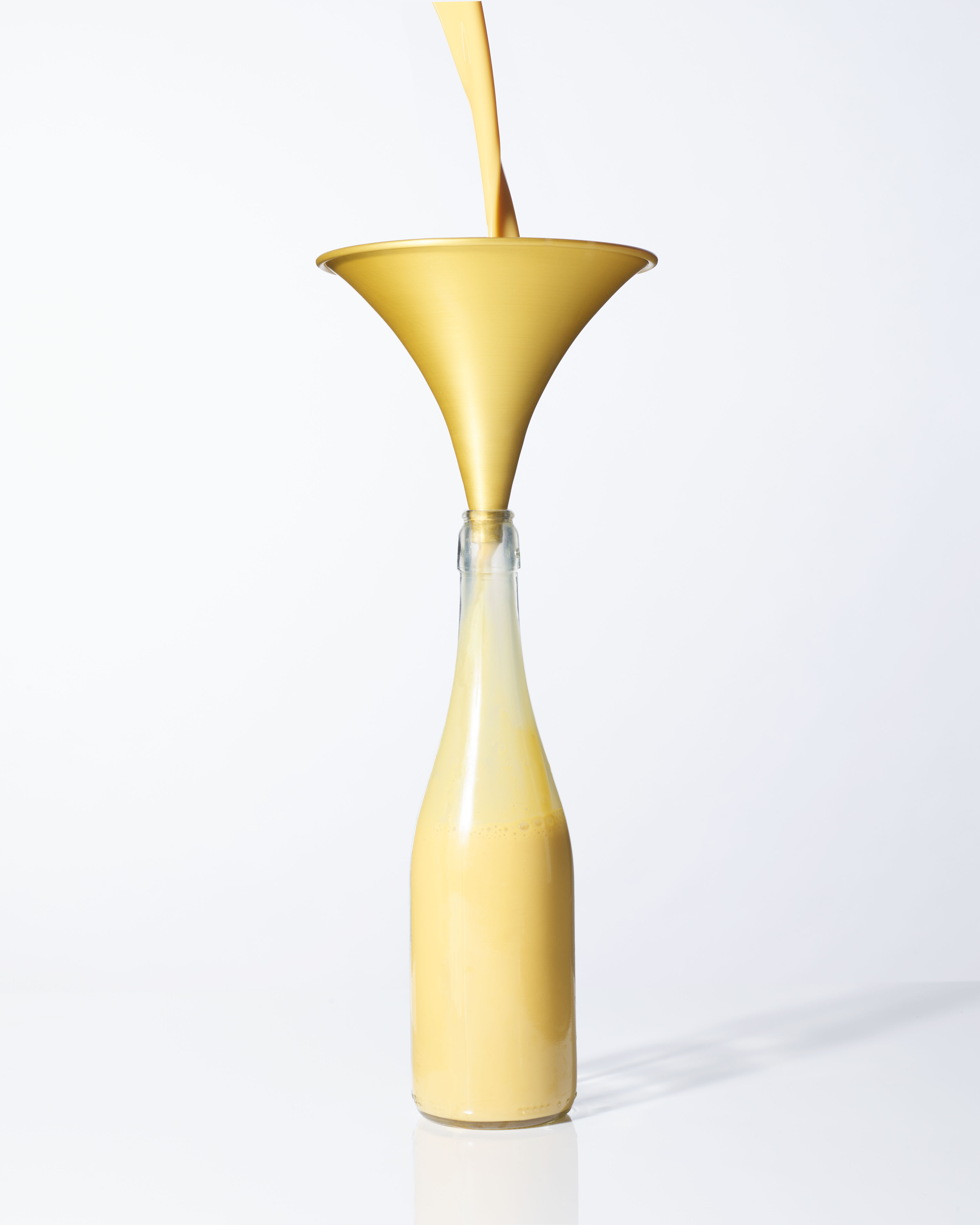 Image of a yellow anodised grammar phone shapped aluminium kitchen funnel with banana milkshake being poured through it into a bottle